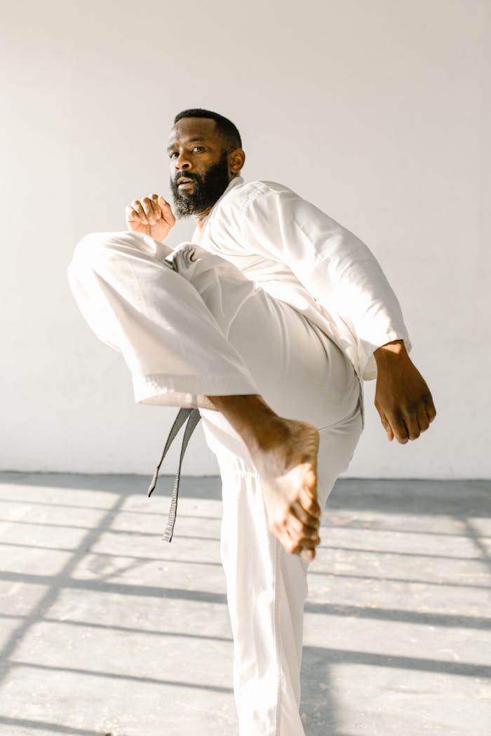 services-02 Bearded martial artist practicing high kick in a sunlit studio